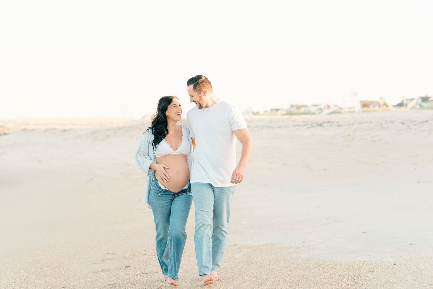 A couple walks down the beach laughing.