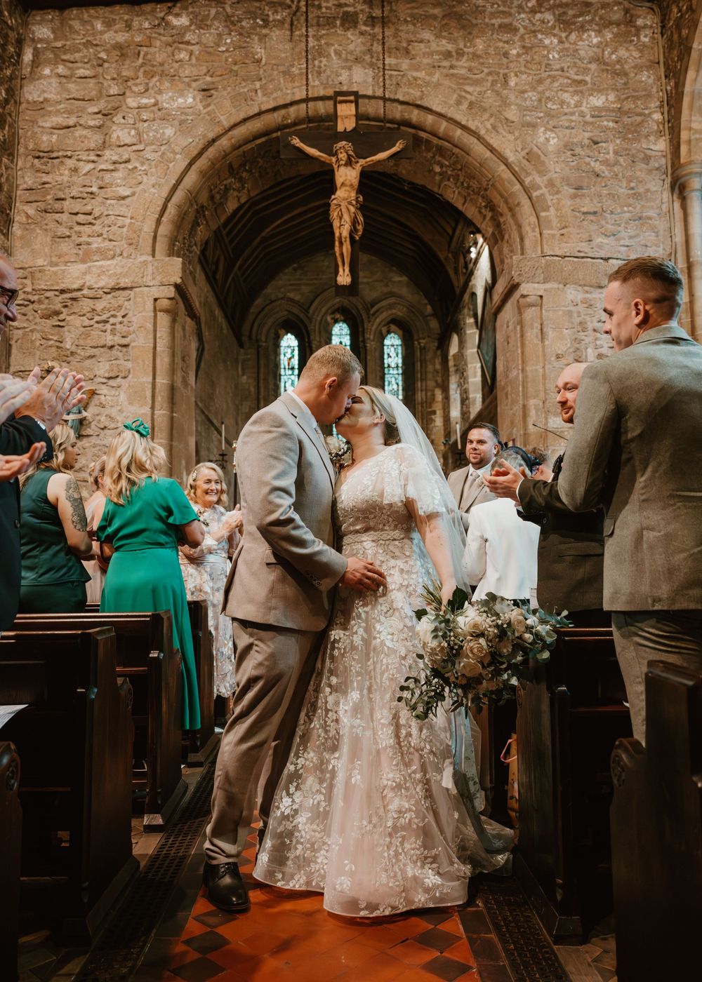 A wedding ceremony in a historic stone church with guests celebrating in the pews.