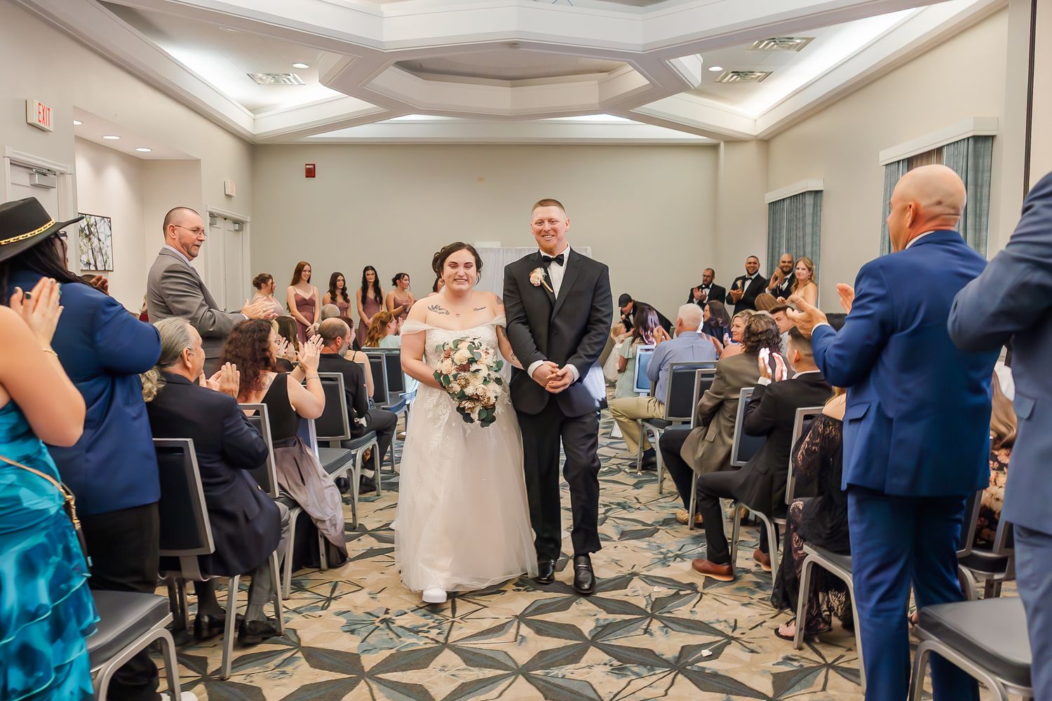 Wedding guests dance and celebrate together in a hotel ballroom during a lively reception party.