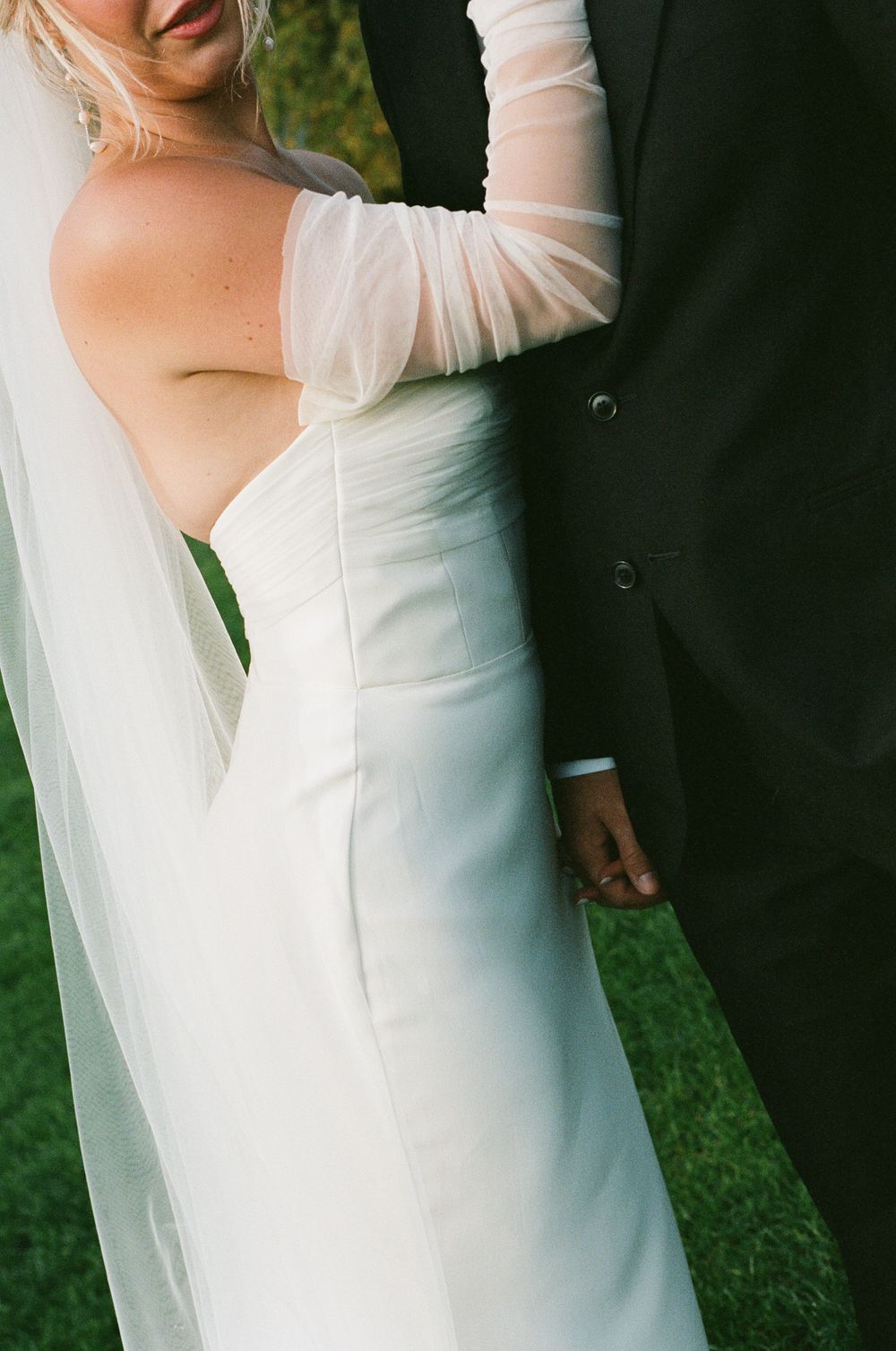 A couple embraces during a wedding photoshoot, with the bride wearing a flowing white dress and sheer sleeves. Paris editorial elopement pho