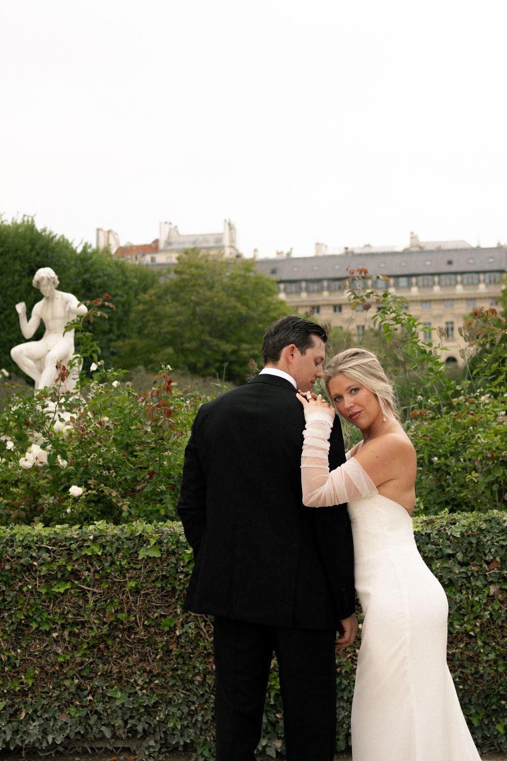 A couple shares romantic moments in a garden setting during their Paris editorial wedding photoshoot, film photography.
