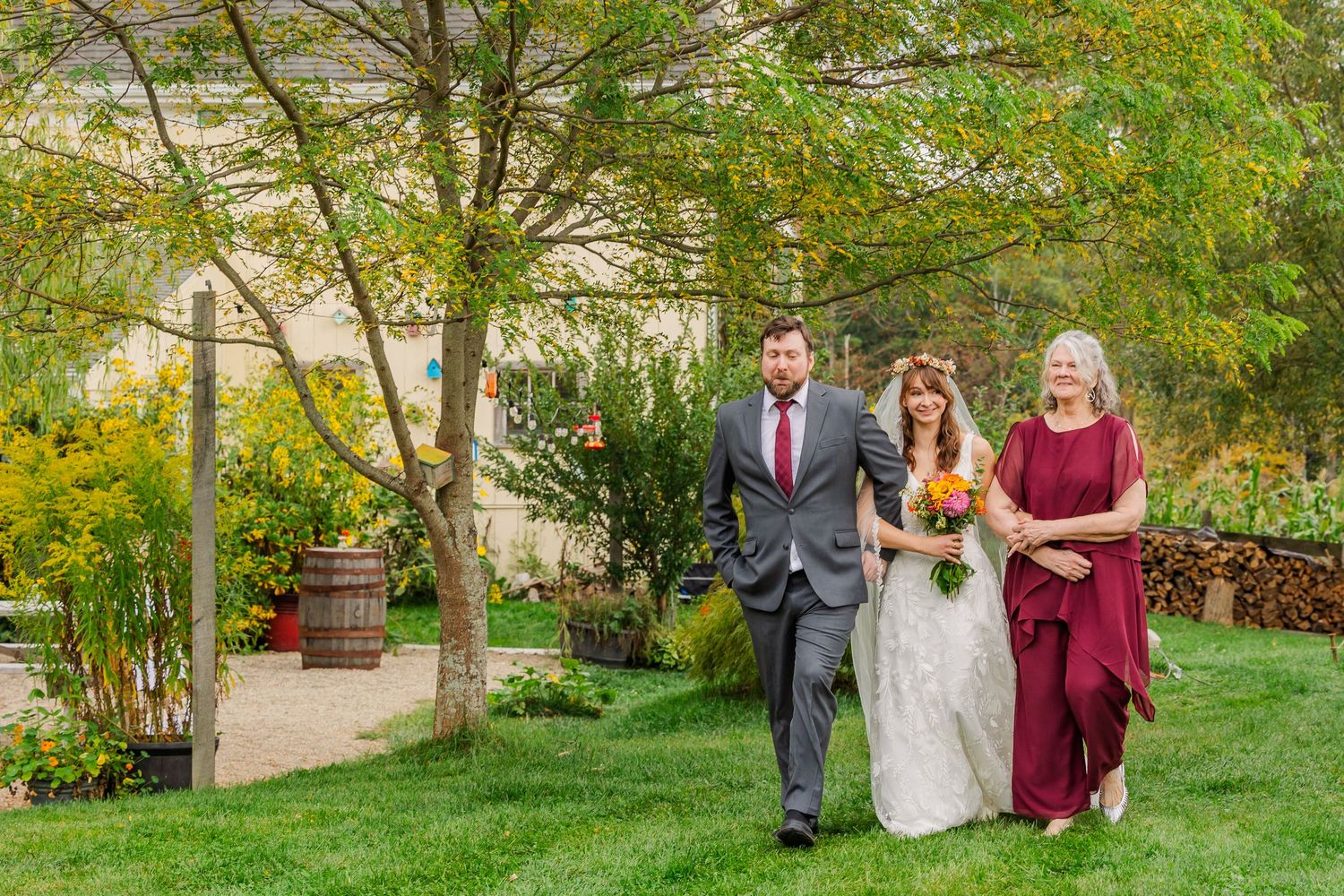 Wedding party poses together on a lush green lawn during an autumn outdoor celebration.