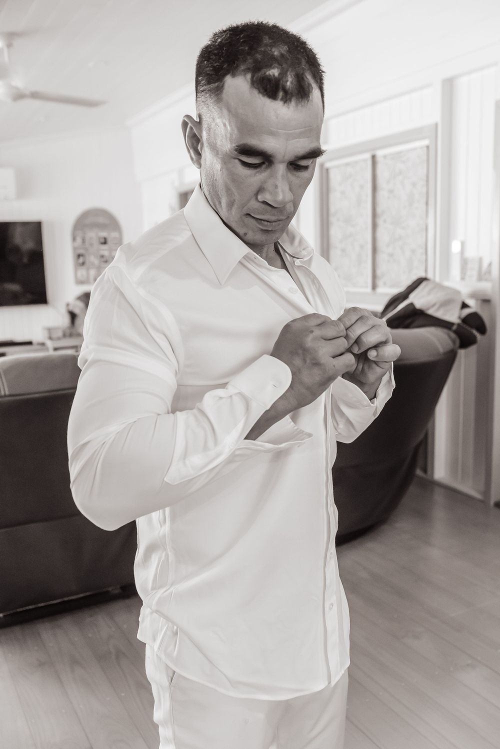 Black and white sequence of someone adjusting a white dress shirt and cuff links while getting ready.