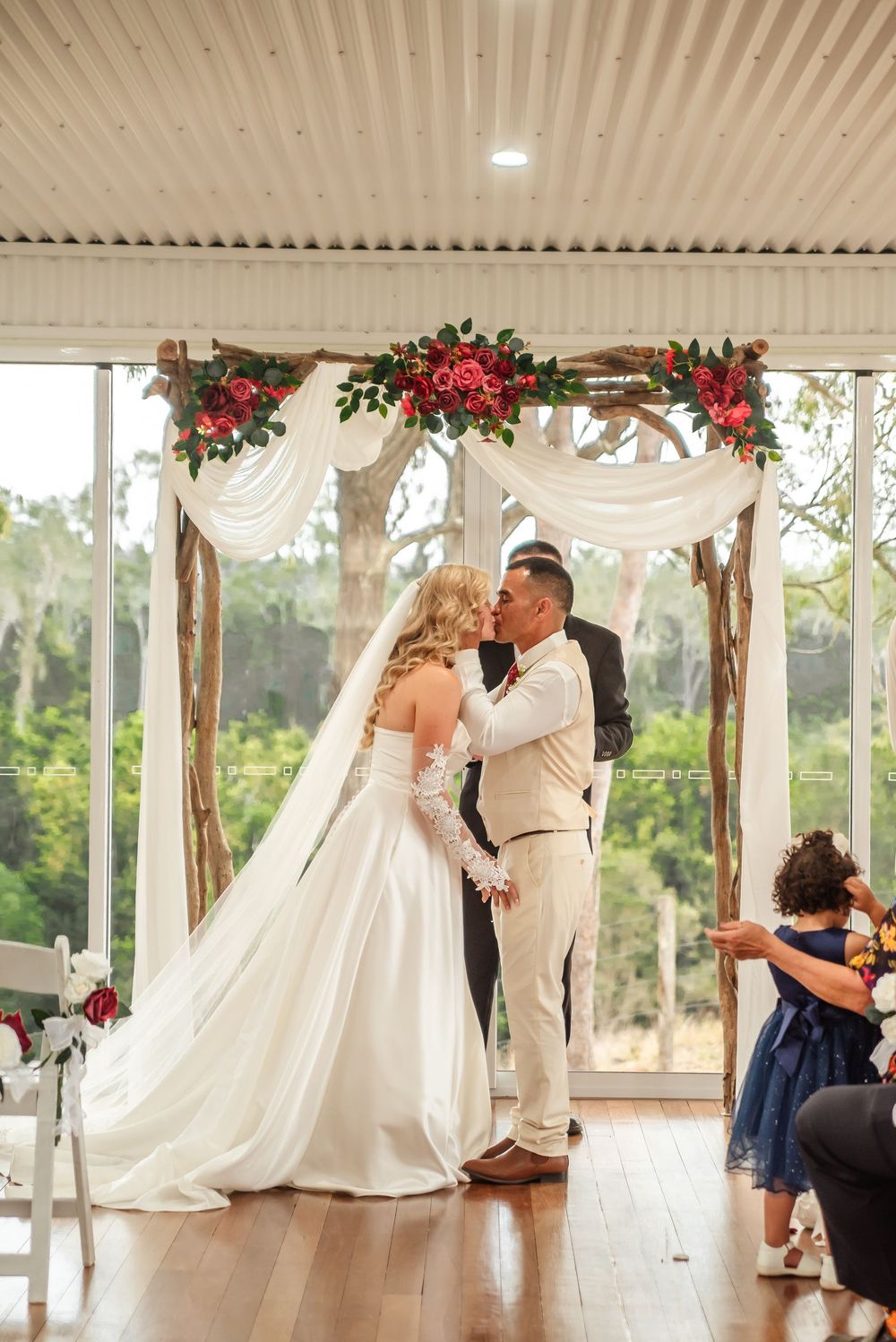 Wedding celebration in an elegant pavilion decorated with red flowers and white draping.