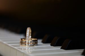 Gold and diamond wedding rings resting on piano keys.