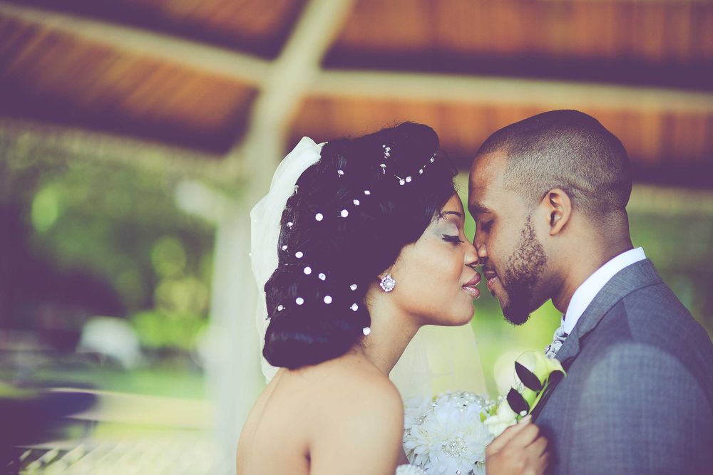 Romantic bride and groom share intimate moment in lush outdoor wedding setting.