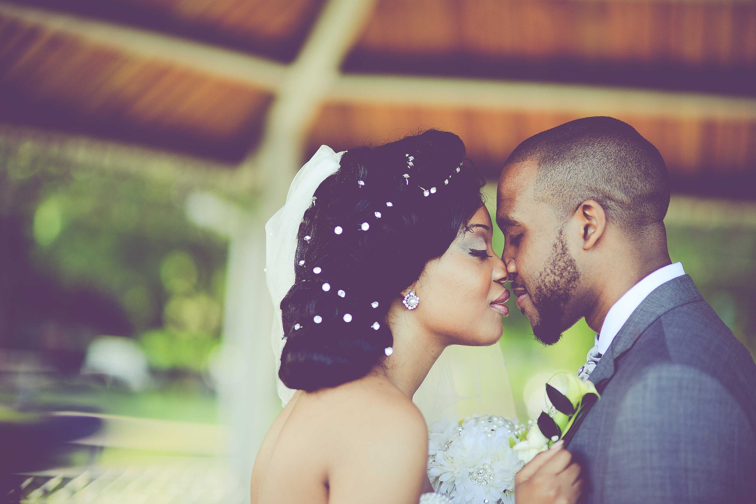 Romantic bride and groom share intimate moment in lush outdoor wedding setting.