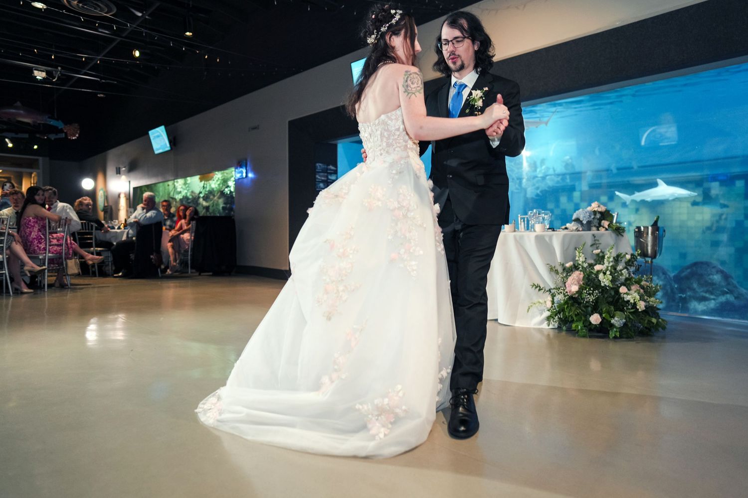 Toledo Zoo & Aquarium Elegant wedding celebration in front of a dramatic blue-lit aquarium display.