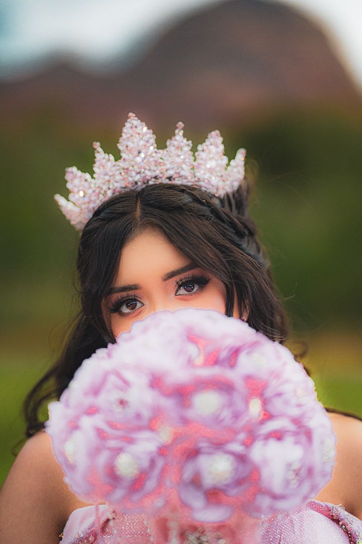 A person wearing a floral crown holds pink cotton candy in front of their face in a creative outdoor photoshoot sequence.
