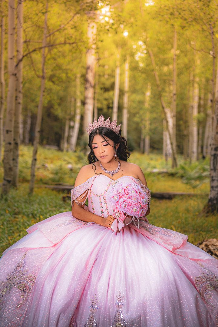 A pink ballgown sparkles in a sunlit aspen forest during a magical outdoor photoshoot.