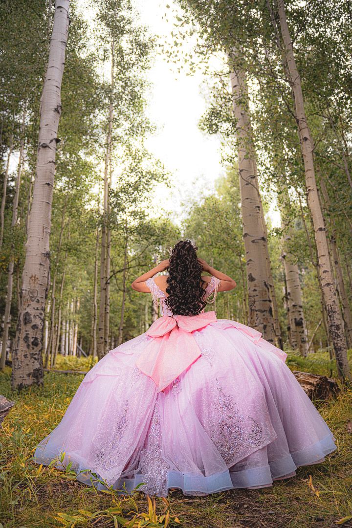 Dramatic pink princess gown with full tulle skirt captured among birch trees in a forest setting.