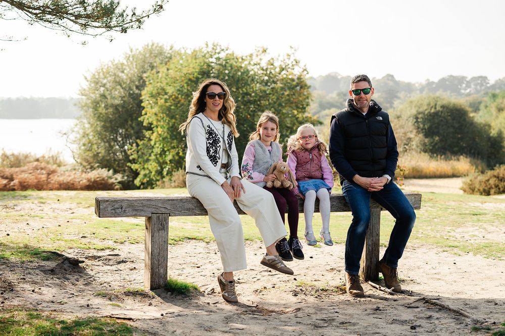 Group sits together on rustic wooden bench in natural outdoor setting during golden hour photography session.