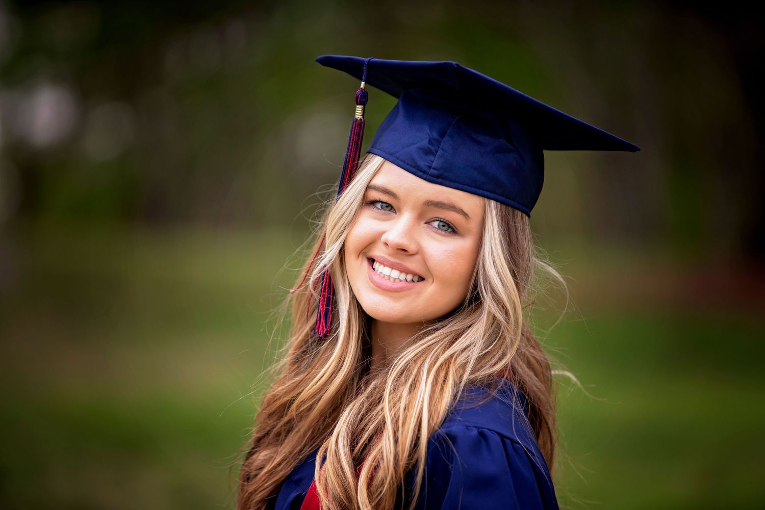 Graduation photos in navy cap and gown against blurred natural background.