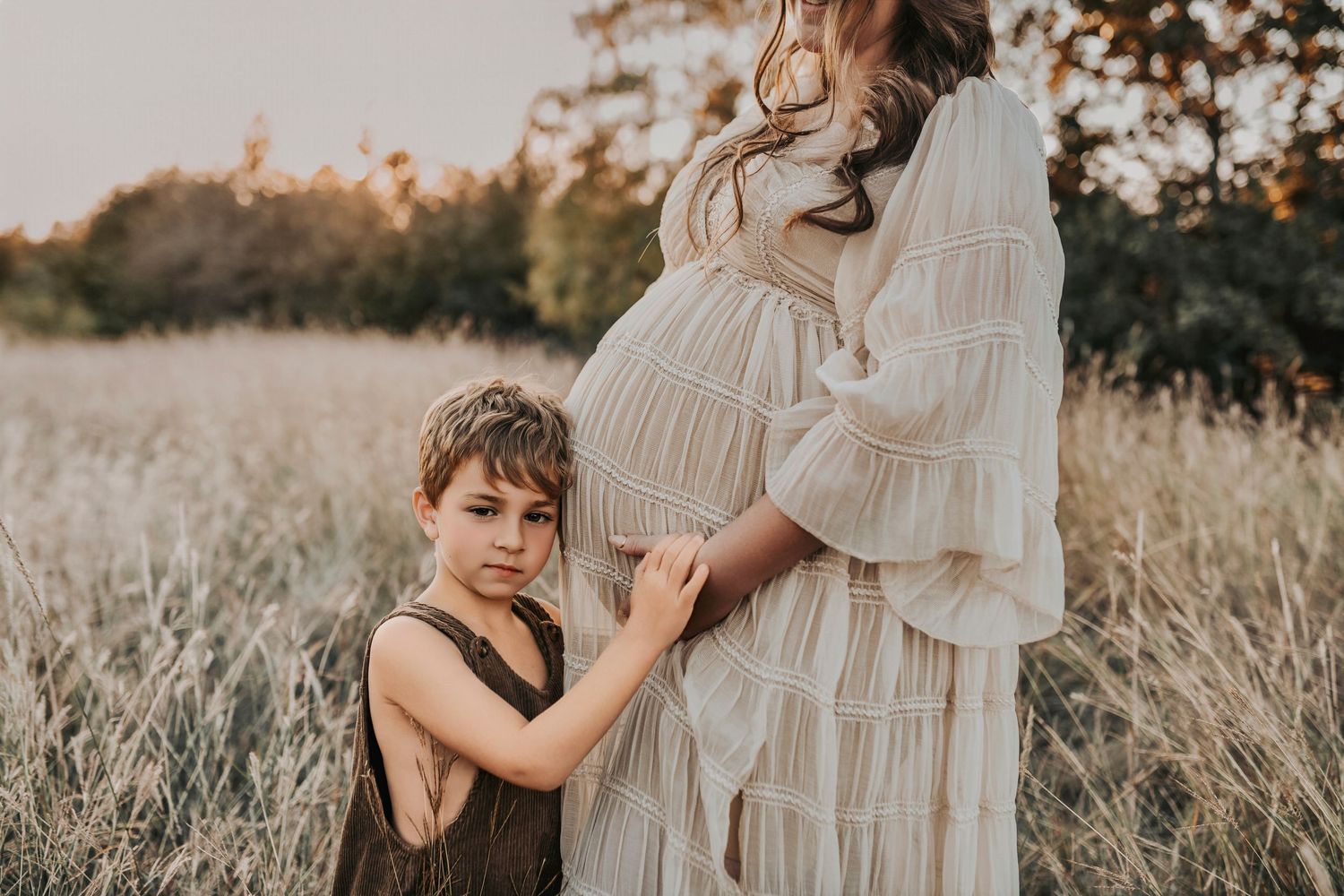 an expecting mother poses for her maternity photos with her precious son who is excited to be a big brother