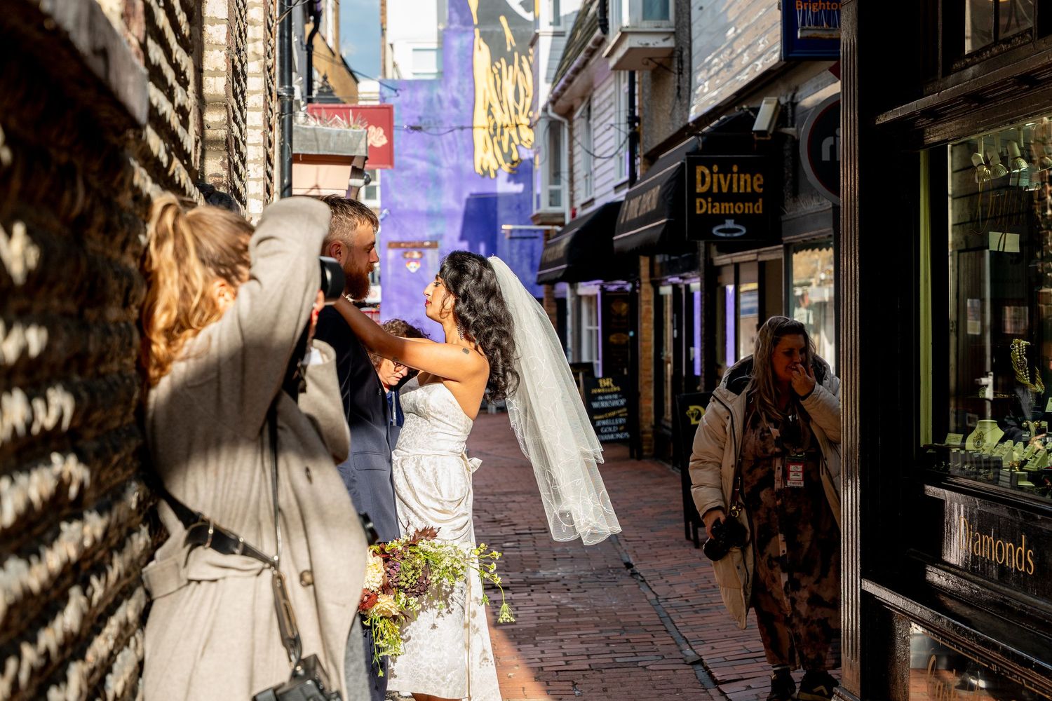A sunlit cobblestone alley in a historic town with shops and storefronts casting dramatic shadows on the street.