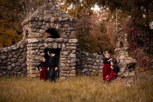 Stone wall archway in autumn forest with red accents and rustic charm creates moody outdoor scene.