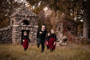Children running and playing together along a stone wall during golden autumn sunset.