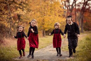 Children walking and laughing together on a path surrounded by golden fall foliage.