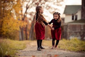 A couple in burgundy sweaters enjoys a playful moment together during an autumn photoshoot in a park.