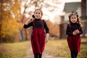 A series of photos showing a child in a red velvet dress walking and playing outdoors during autumn.