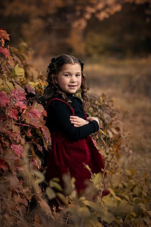 A series of autumn portraits showing a child in a burgundy dress among colorful fall foliage at sunset.