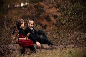 Romantic couple embraces in autumn forest setting with warm lighting and rustic brown tones.