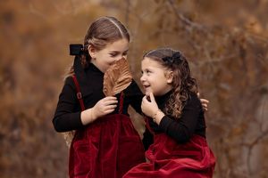 Two people in burgundy sweaters share a tender moment outdoors during autumn.
