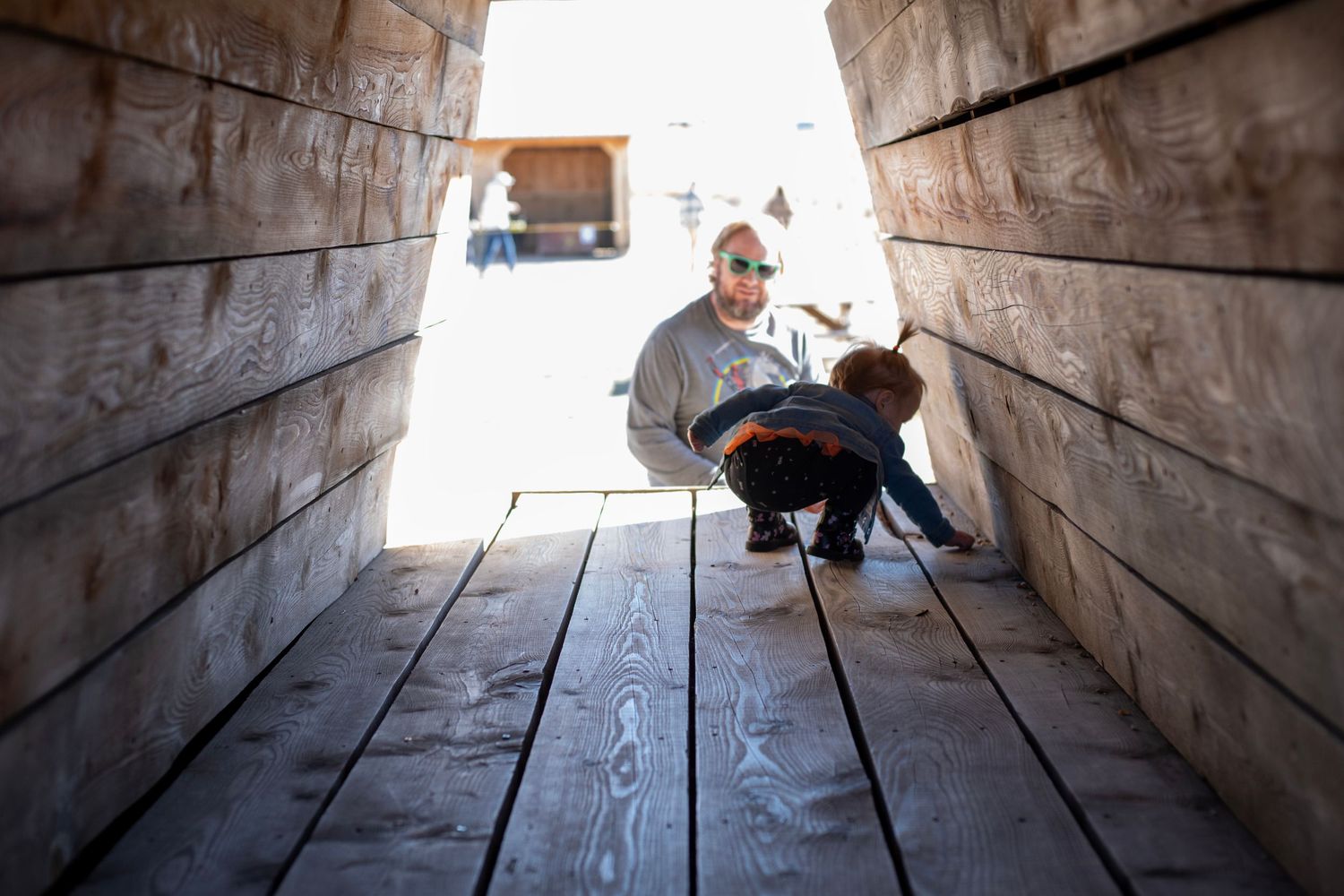 A sequence of photos showing movement through a wooden tunnel leading to a bright exit.