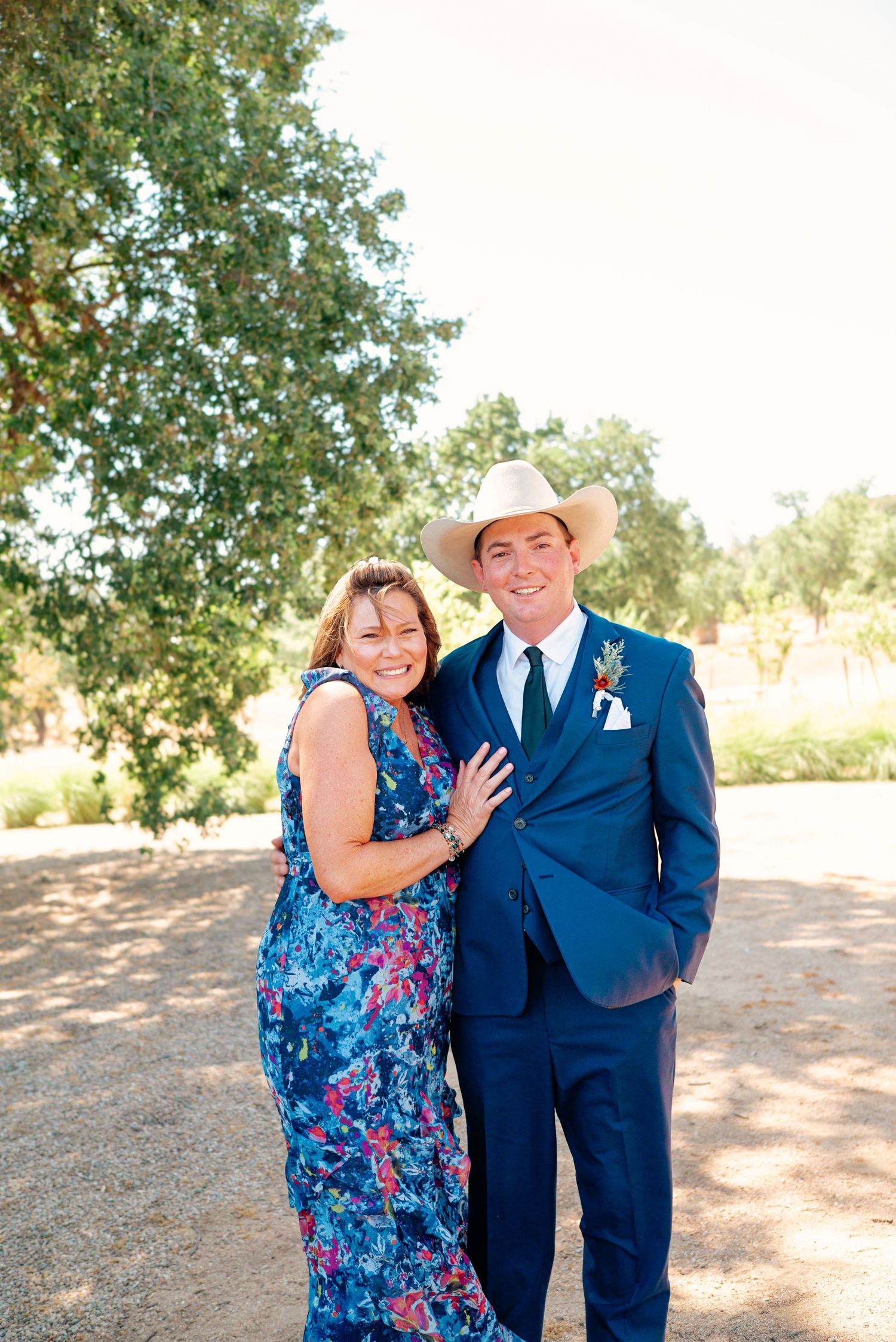 Outdoor wedding portraits taken under green leafy trees on a sunny day.
