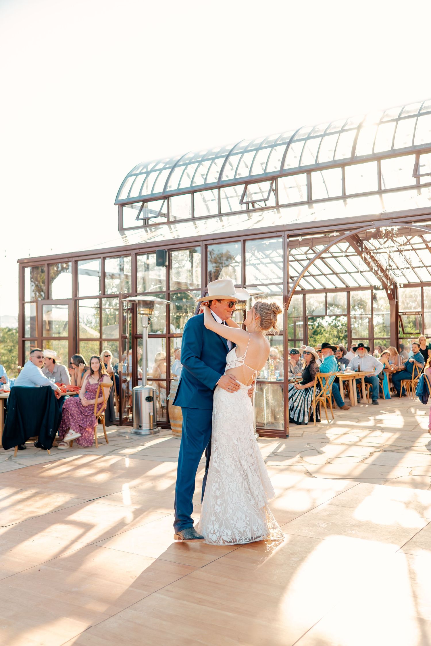 Couple shares their first dance in a sunlit greenhouse wedding venue.