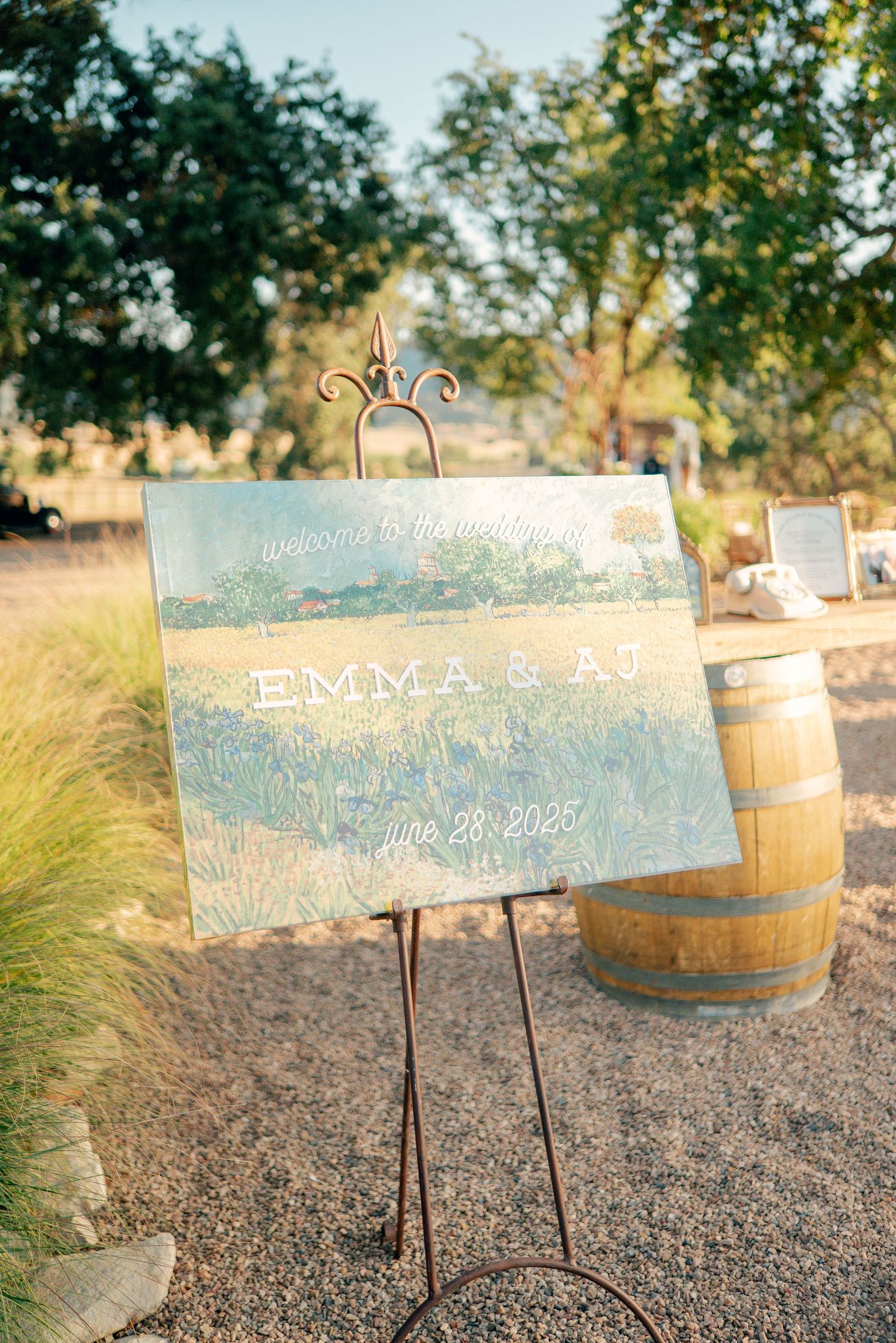 Wedding welcome sign on an easel next to rustic wine barrel at outdoor venue.