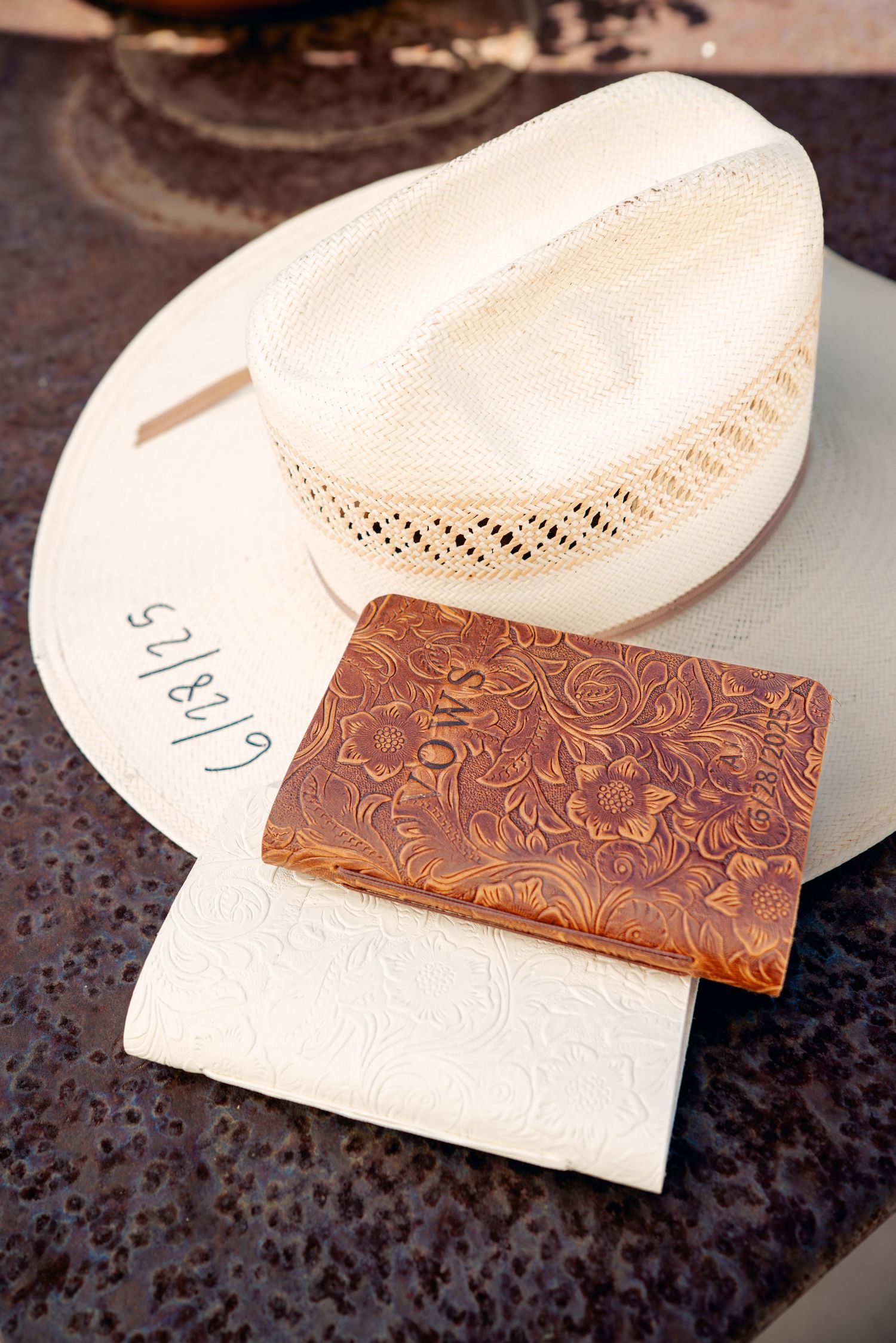 White cowboy hat and leather wallet with embossed pattern on dark surface.