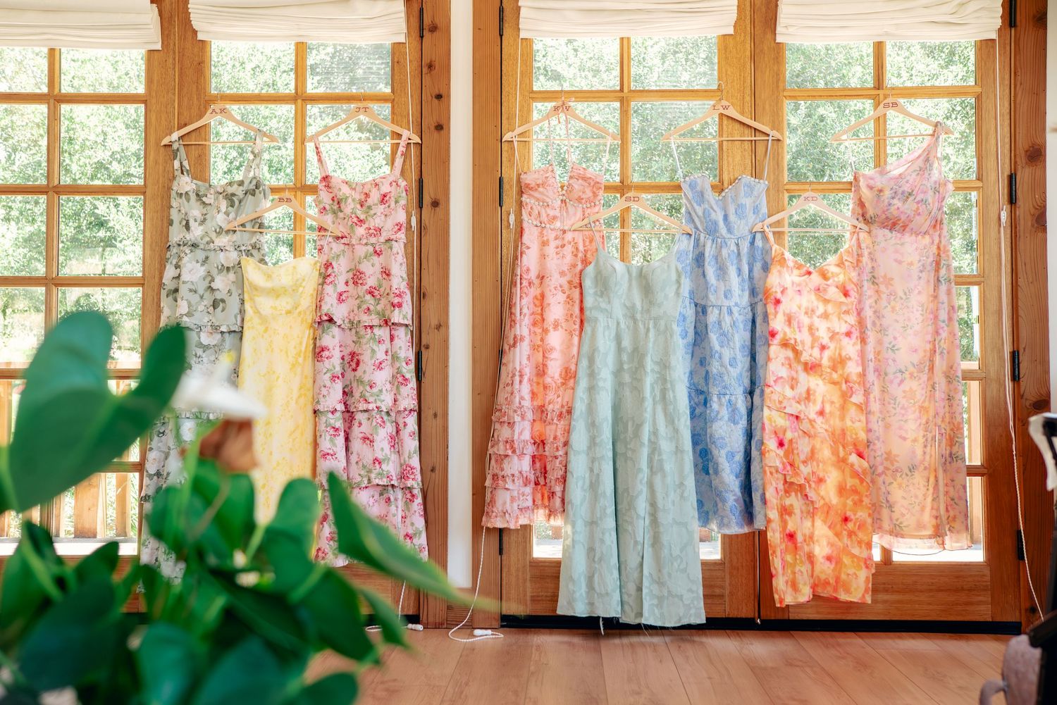 Colorful bridesmaid dresses hanging on display in a sunlit room.