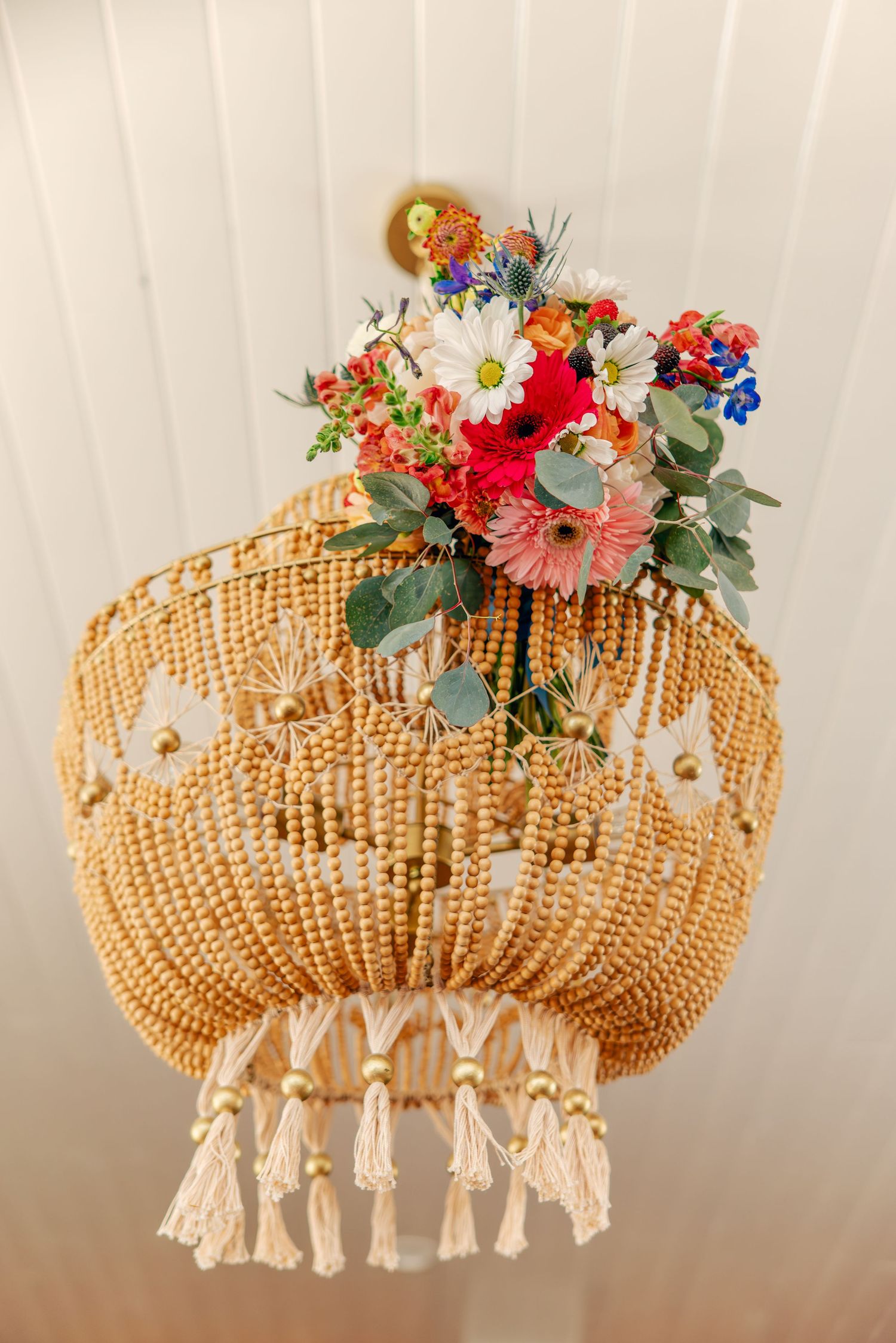 Decorative beaded chandelier adorned with colorful fresh flowers and tassels.