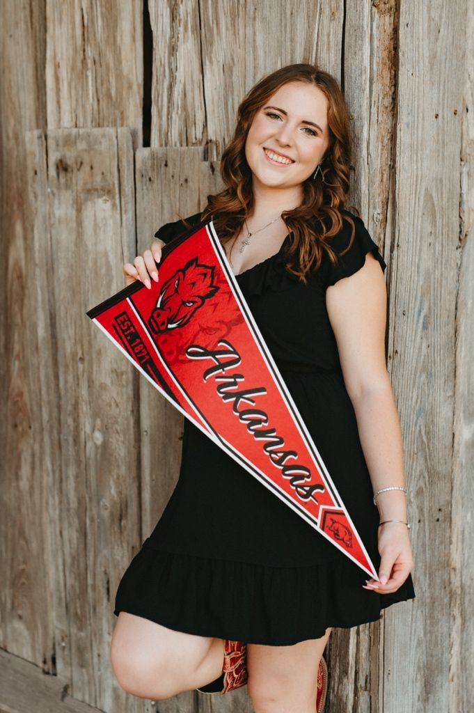 A series of four maternity photos showing someone in a black dress holding red graduation pennants against a wooden wall.
