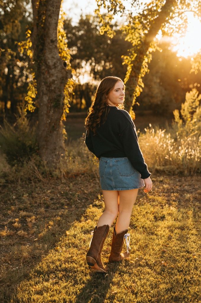 Stylish brown boots and denim shorts captured in golden sunset light against autumn foliage.