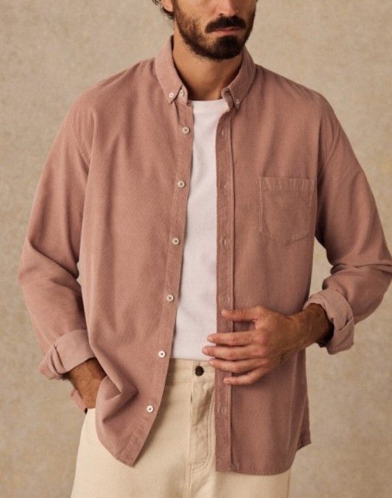 Man wearing a dusty rose button-down corduroy shirt over a white tee with beige pants.