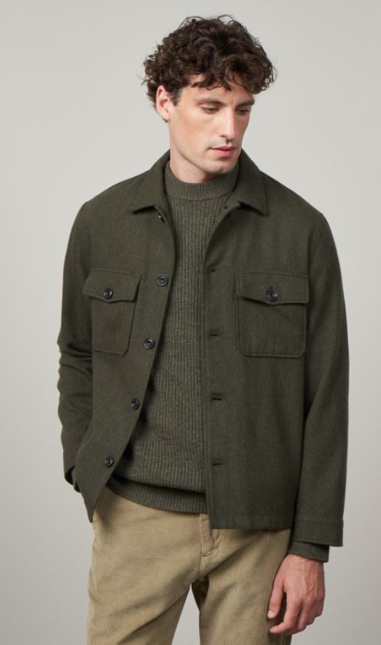 Olive green military-style jacket paired with ribbed sweater and khaki pants for a casual masculine look.