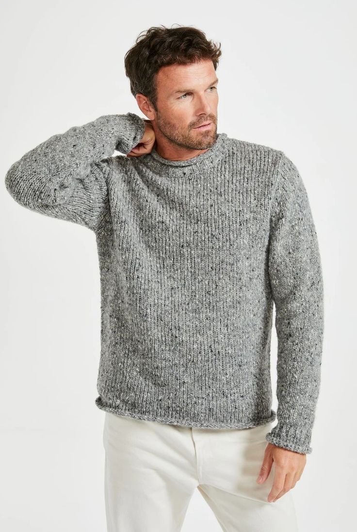 Man wearing a grey marled ribbed knit crewneck sweater with a relaxed fit, paired with white pants.