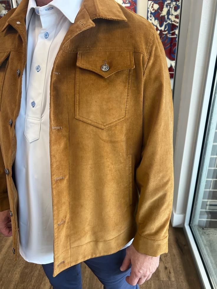 Man wearing a vintage tan suede jacket over a white shirt with blue jeans, showcasing a chest pocket detail.