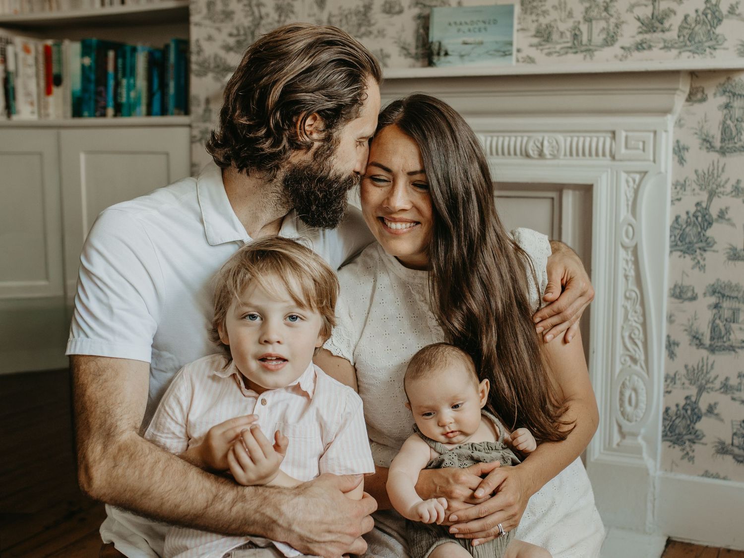 A happy family of four shares a joyful moment together in their cozy living room Newborn photographer london