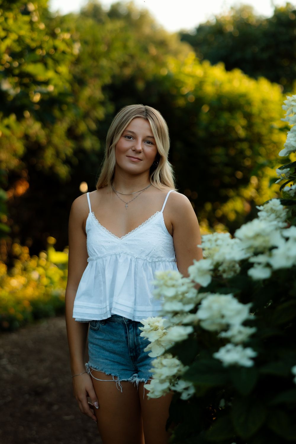 A series of outdoor summer portraits with white flowers and denim shorts against a natural garden backdrop.