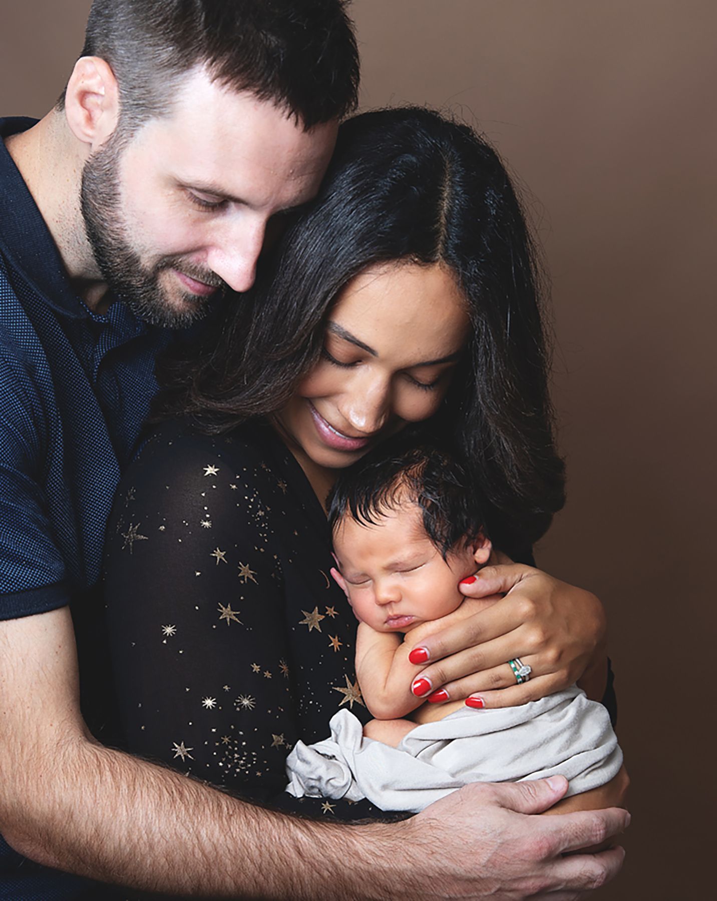A tender family moment showing parents embracing their baby during a newborn session in a Bexley photography studio