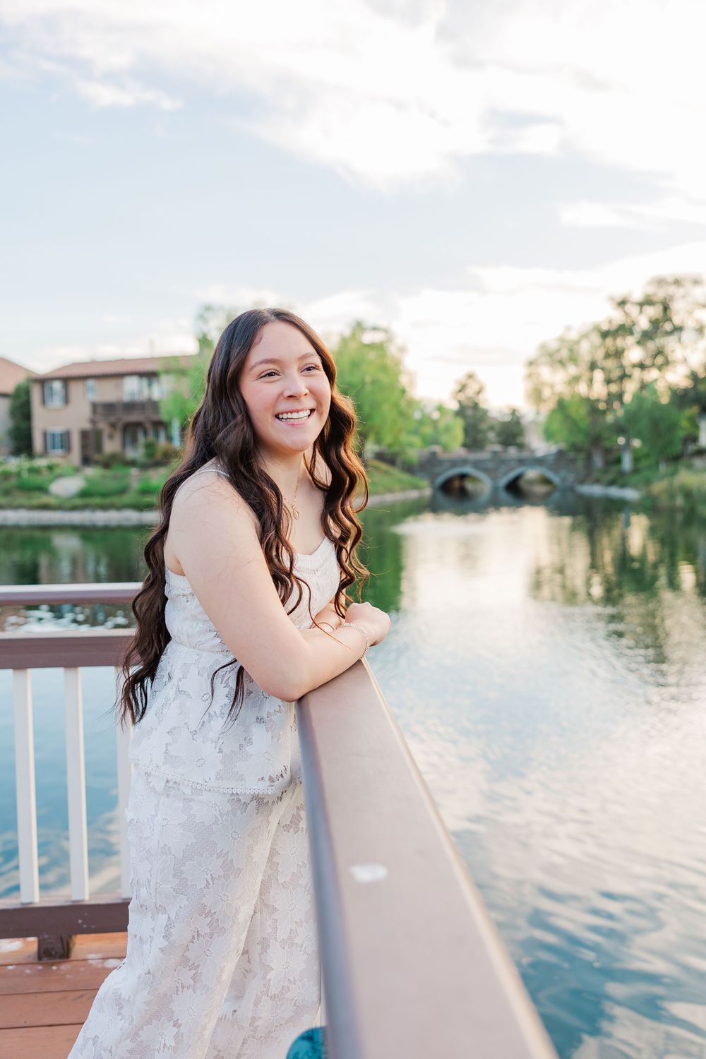 Posing on a wooden dock by a serene lake at sunset in an elegant white dress.