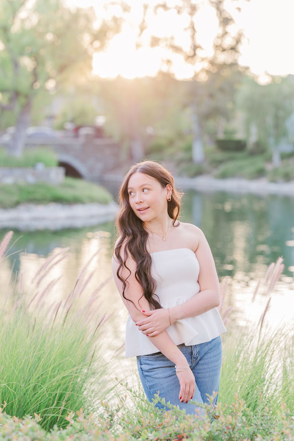 Casual outdoor photoshoot by a lake with natural lighting and grass in the foreground.