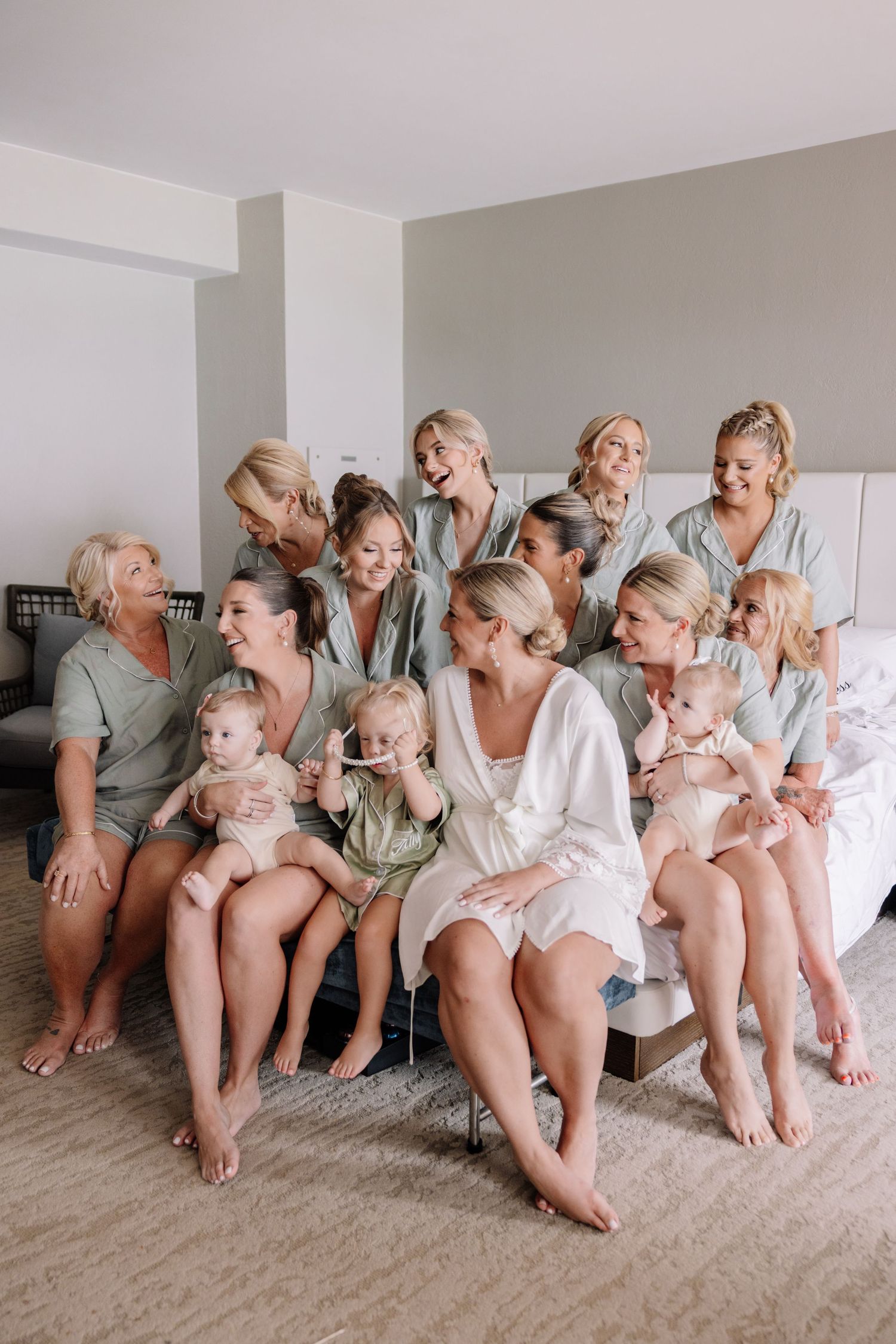 Wedding party in matching robes sitting together on carpeted floor.