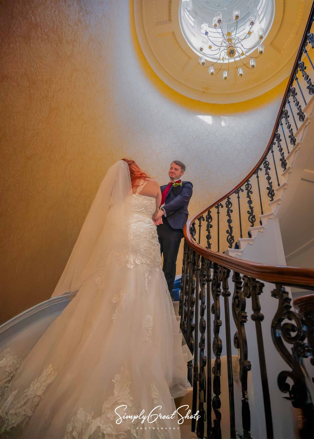 A bride and groom meet on the spiral staircase at Eastwood Hall.