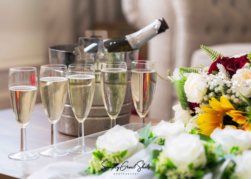 Eastwood Hall bridal preparations under way with champagne glasses and a floral bouquet with deep red and cream roses.