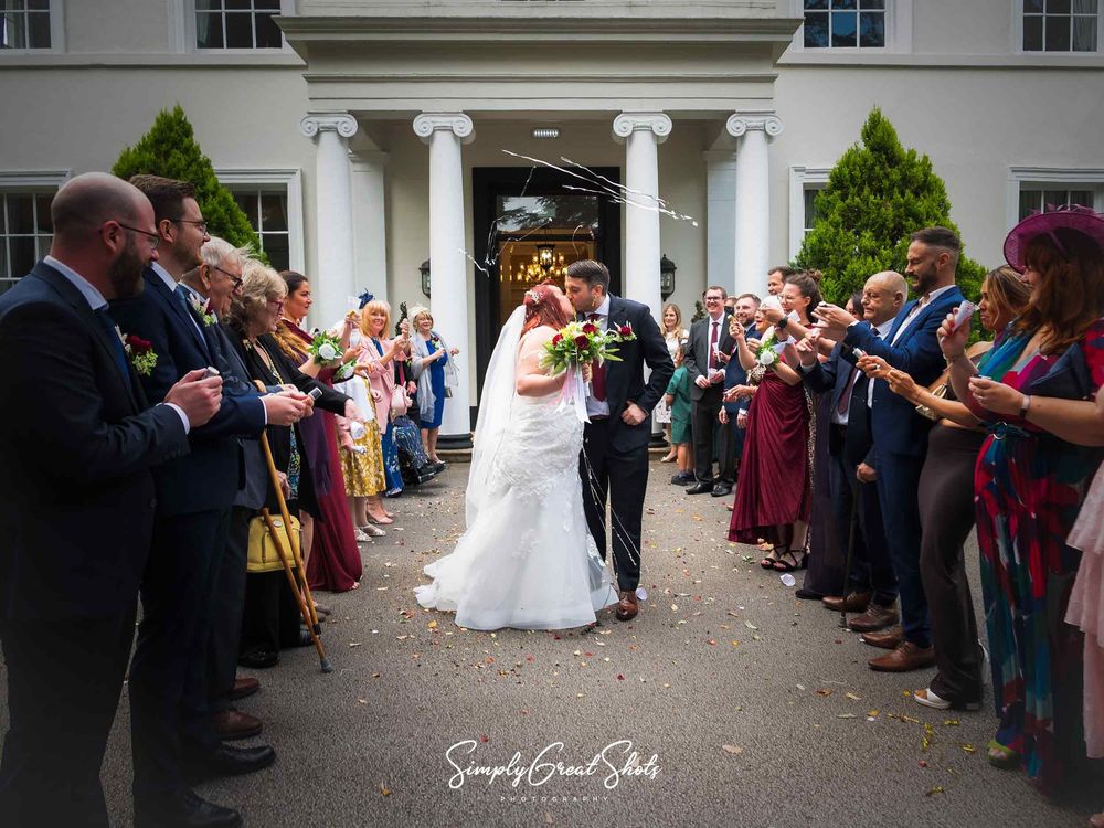 A bride and groom stop for a kiss on their exit photograph with sparklers and confetti in the air.