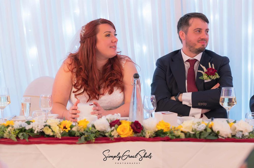 A newly married couple sit smiling on the top table in the Chatterley suite at Eastwood Hall